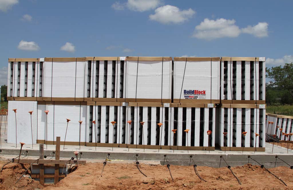 Large stack of newly delivered ICF blocks at a construction site, ready for building an insulated concrete forms foundation or pool.